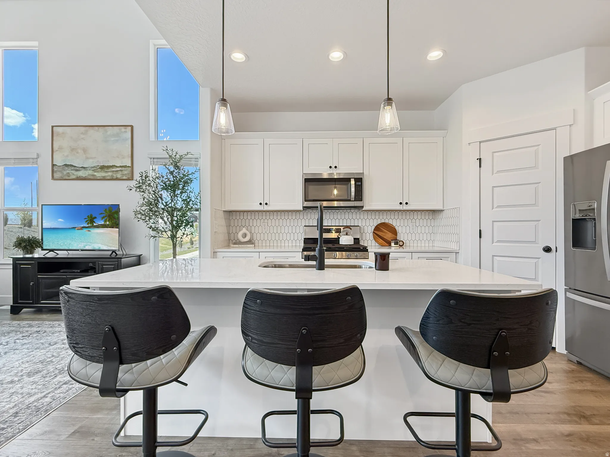 Kitchen with a kitchen island with sink, backsplash, a kitchen breakfast bar, and white cabinets