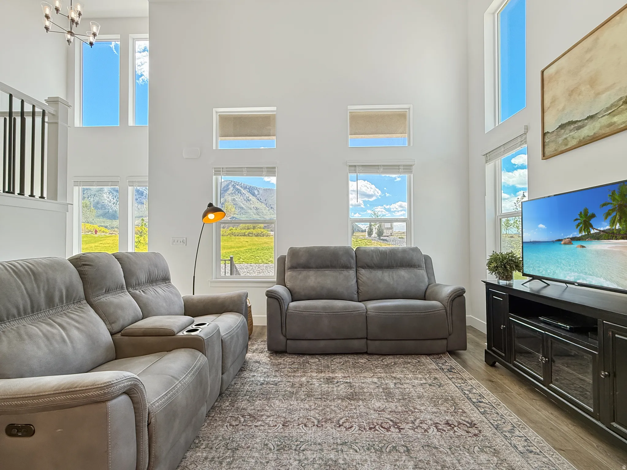 Living room featuring a high ceiling, wood finished floors, healthy amount of natural light, and hanging lights
