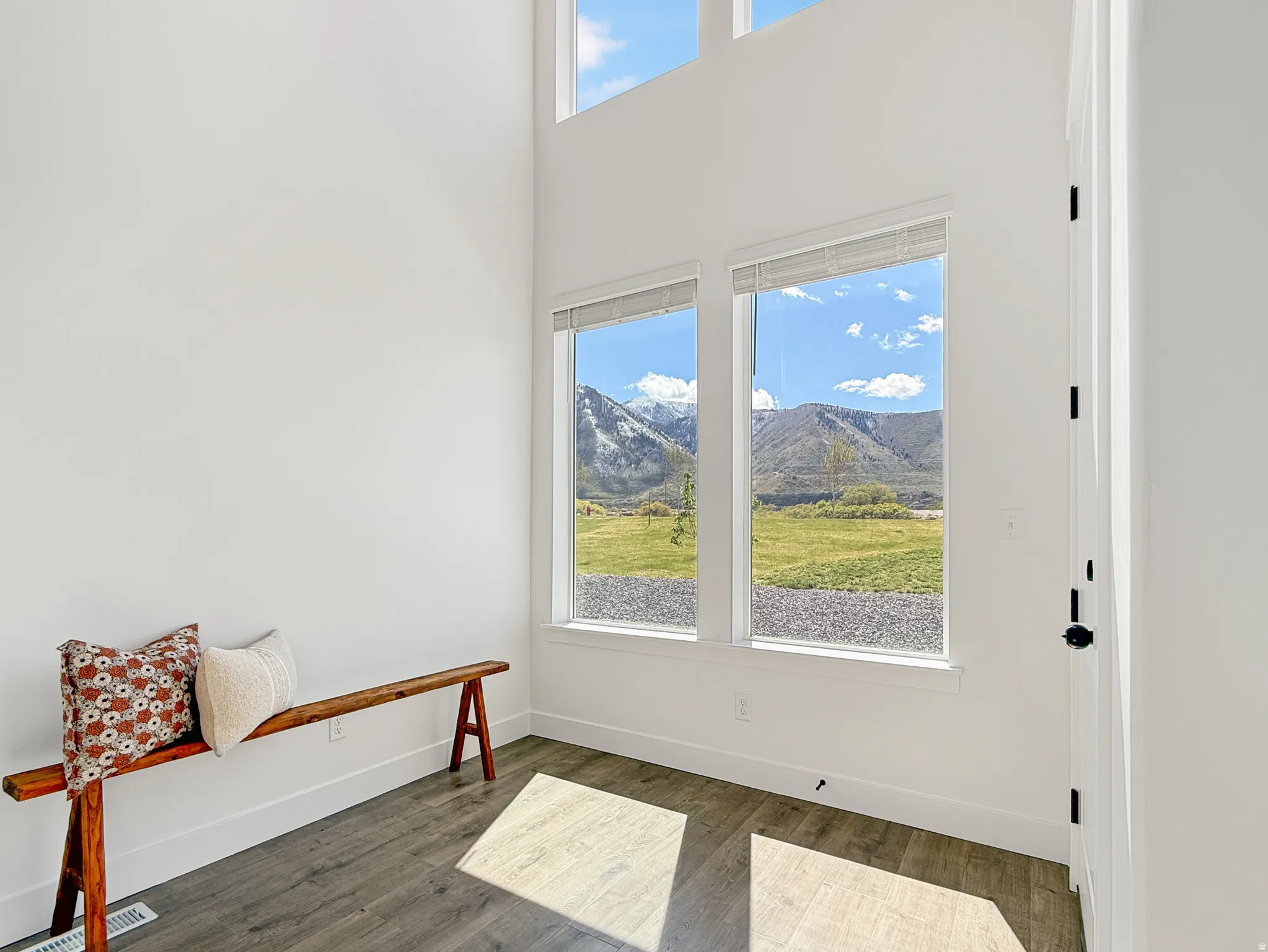 Interior space with dark wood-style flooring, a high ceiling, and a mountain view