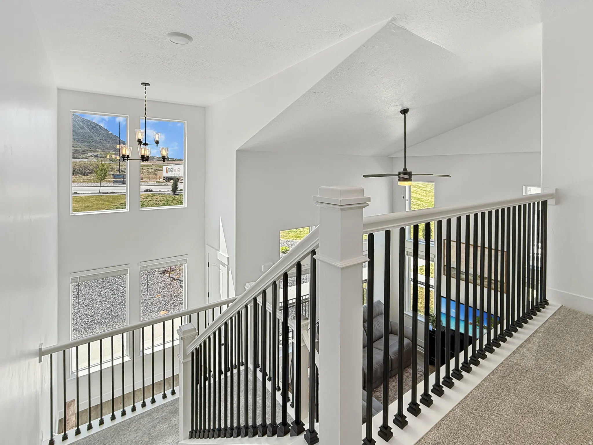 Corridor with carpet floors, an upstairs landing, a high textured ceiling, and suspended lighting