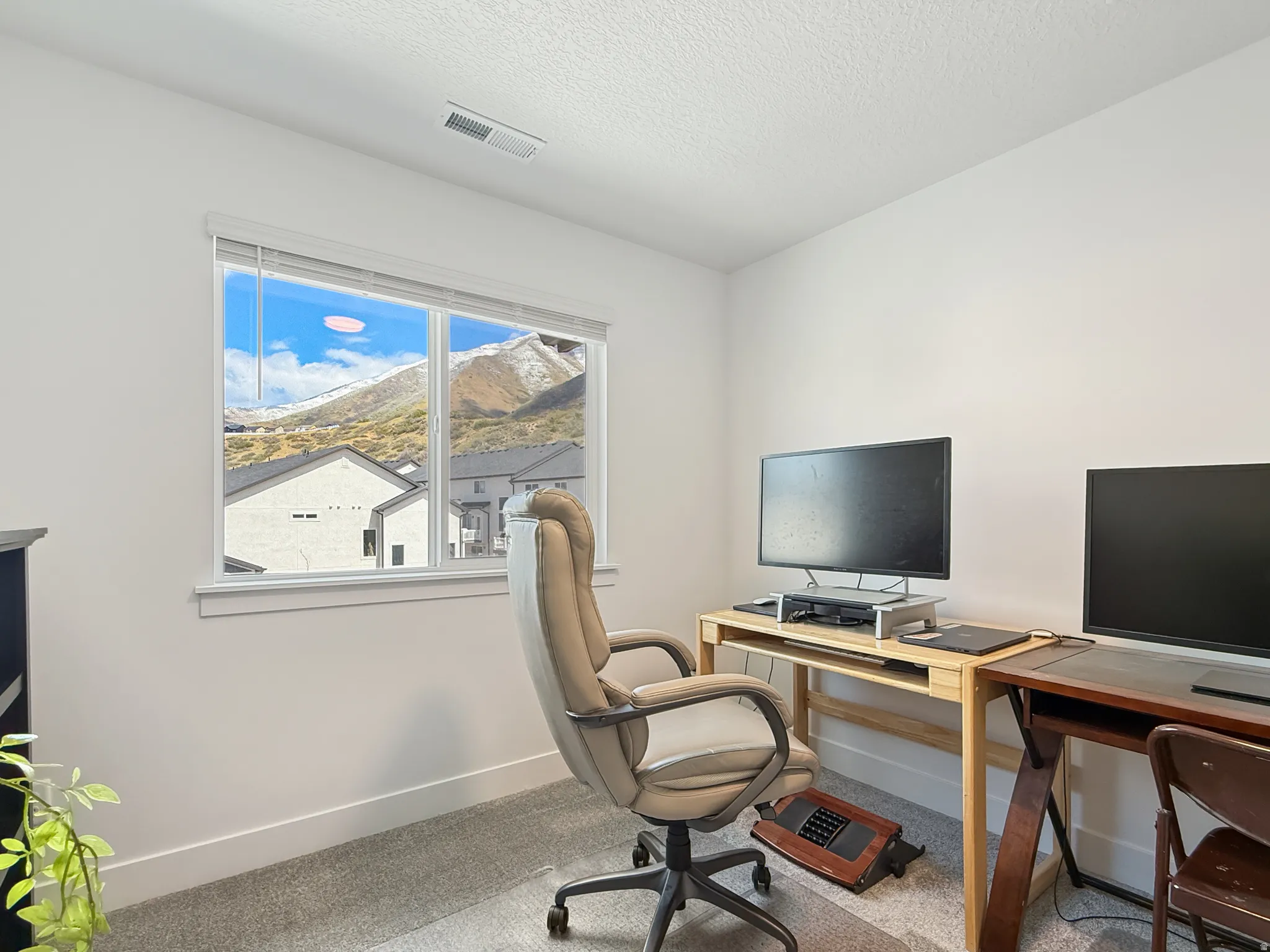 Office with light colored carpet and a textured ceiling