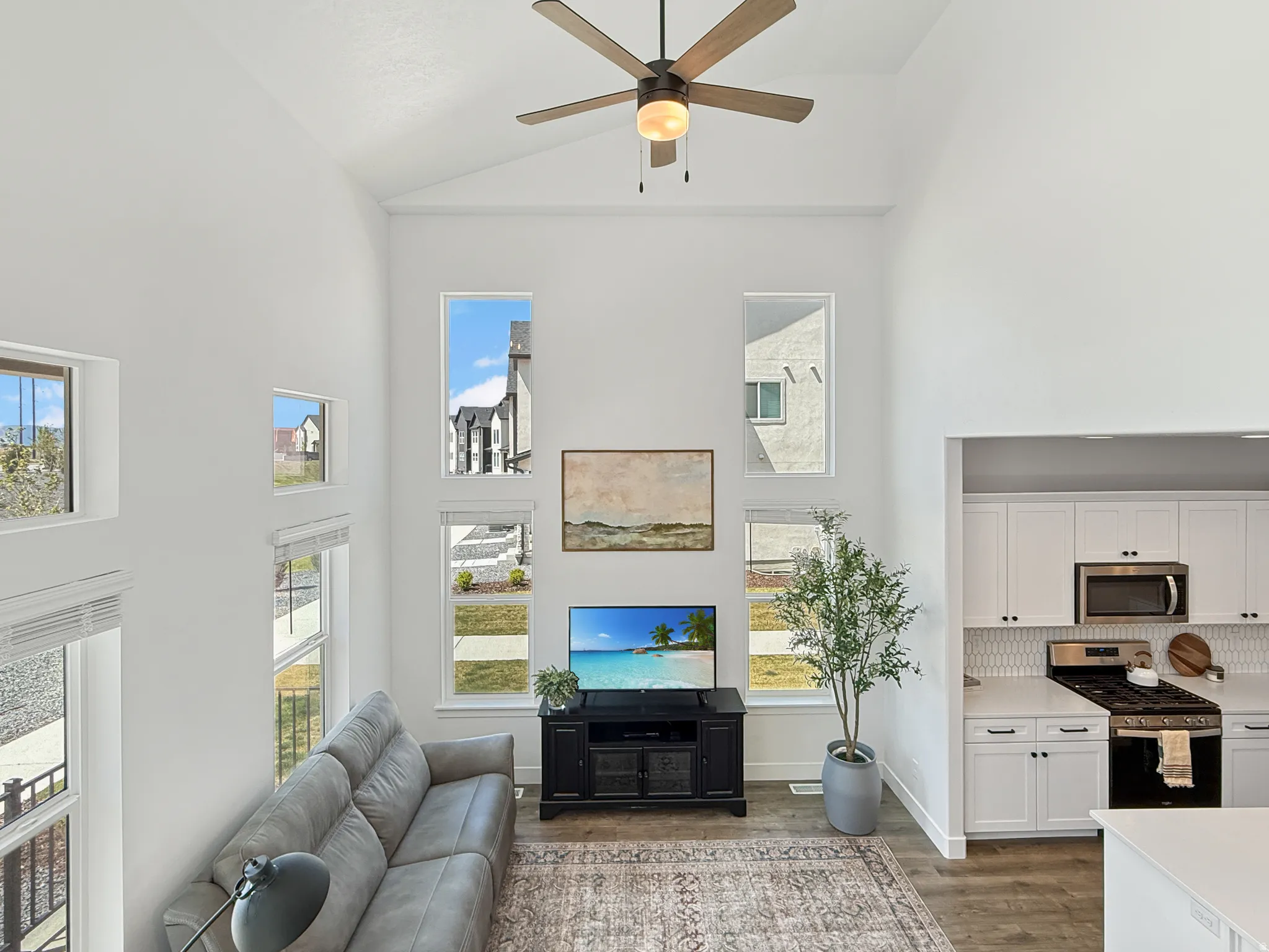 Living area with a ceiling fan, light wood finished floors, plenty of natural light, and vaulted ceiling