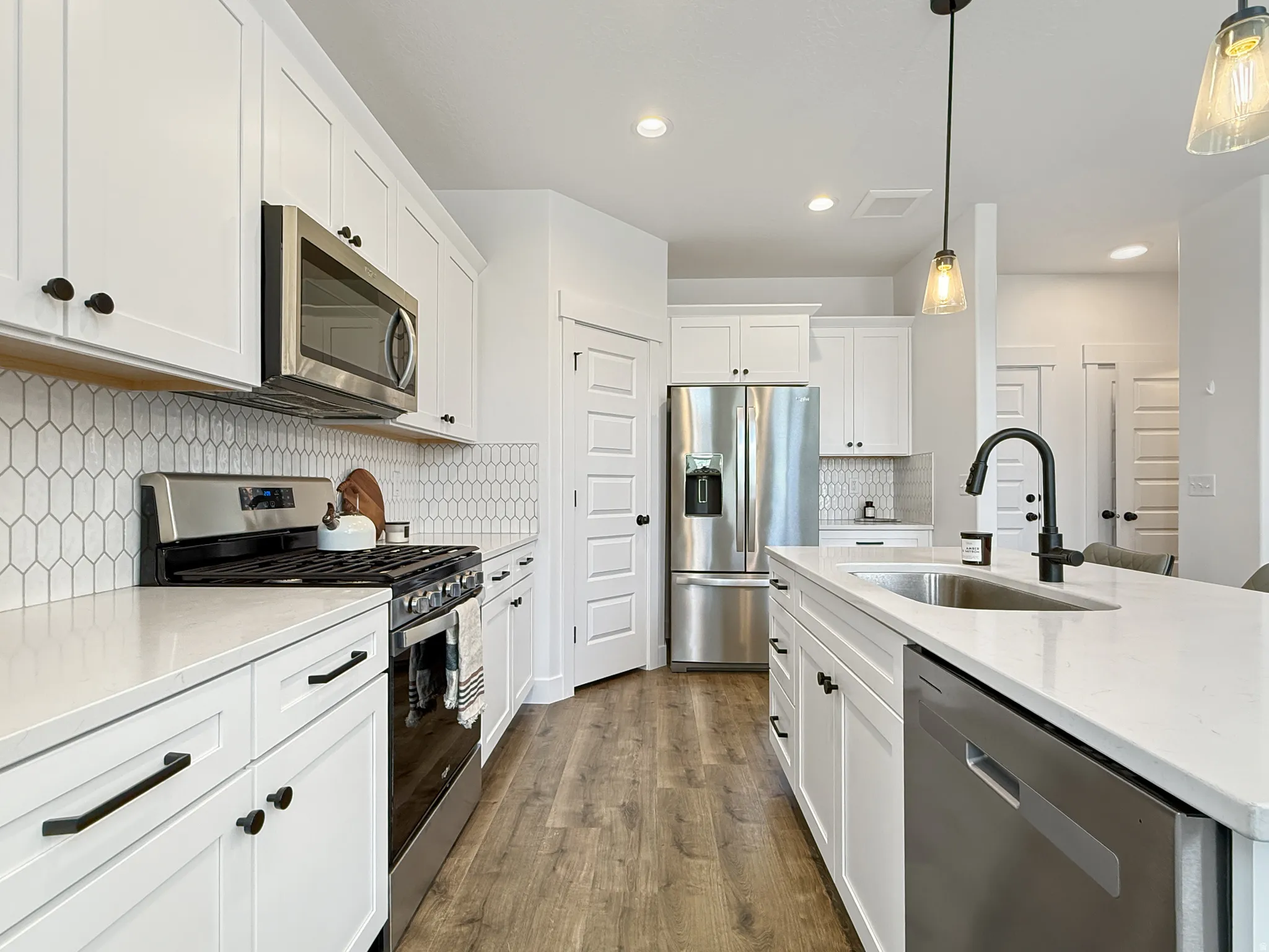 Kitchen featuring stainless steel appliances, light stone counters, and white cabinets