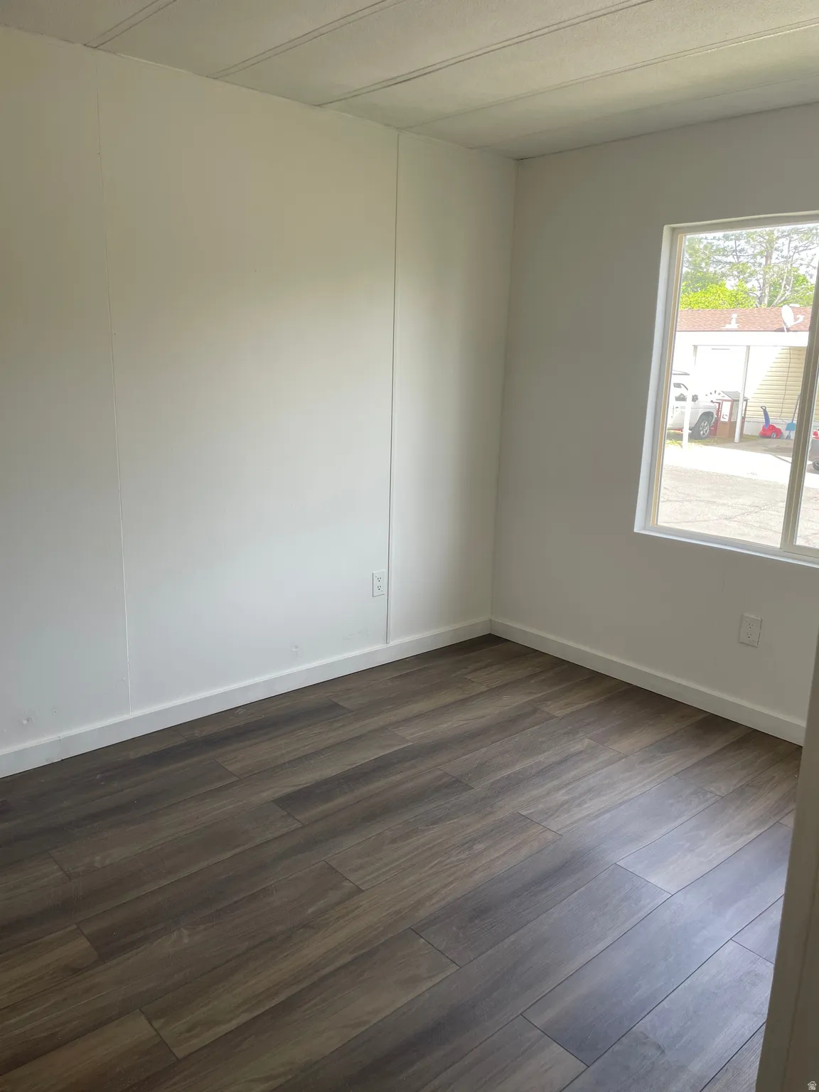 Unfurnished room with dark wood-type flooring and baseboards