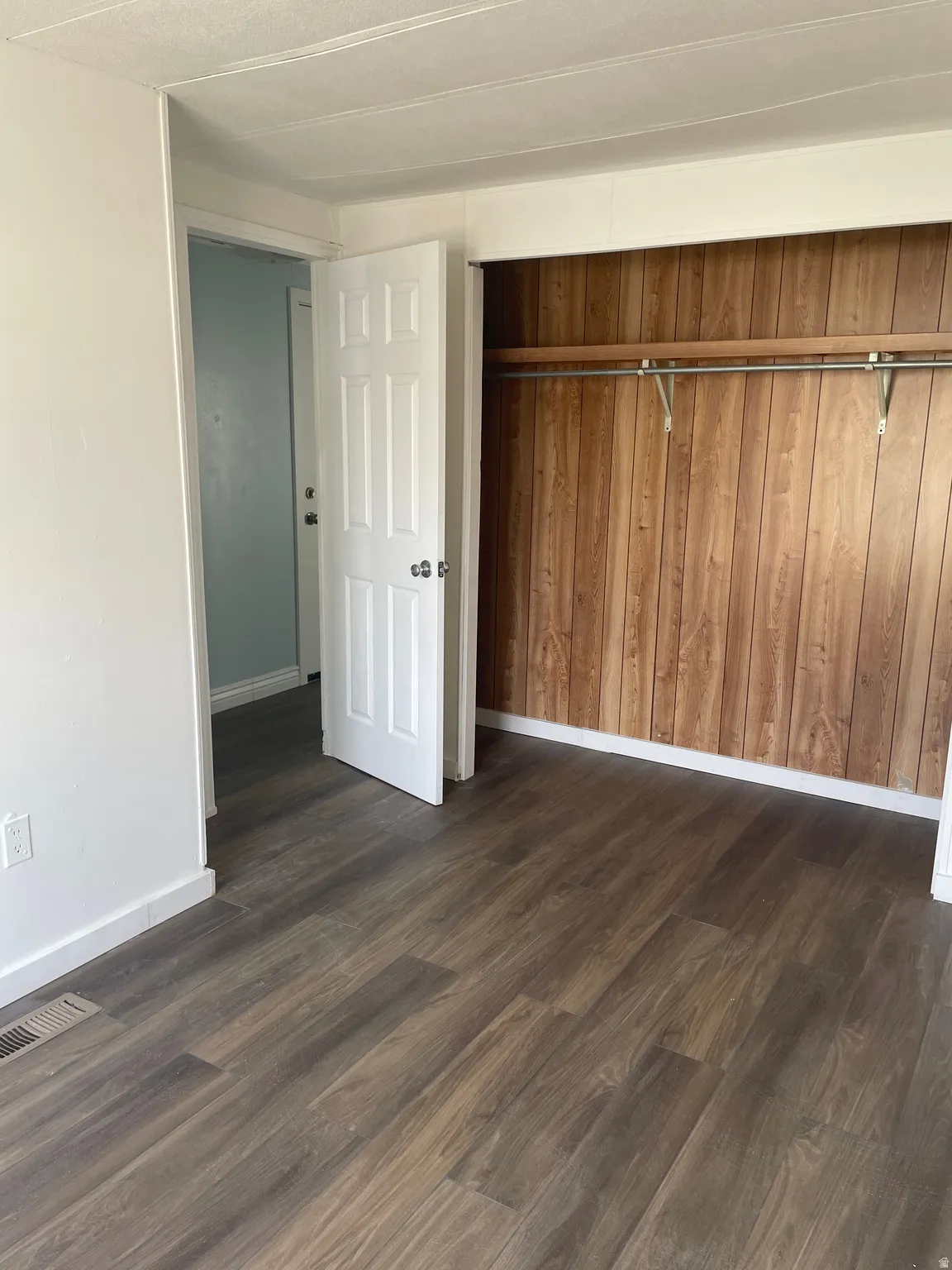 Unfurnished bedroom with dark wood-style floors and a closet