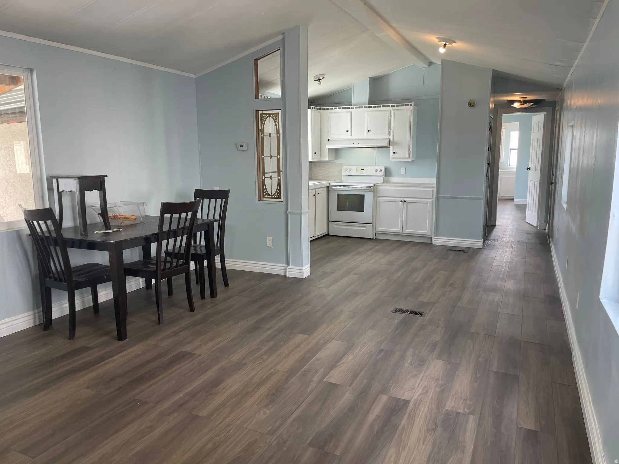 Dining space with beamed ceiling and dark wood-style floors