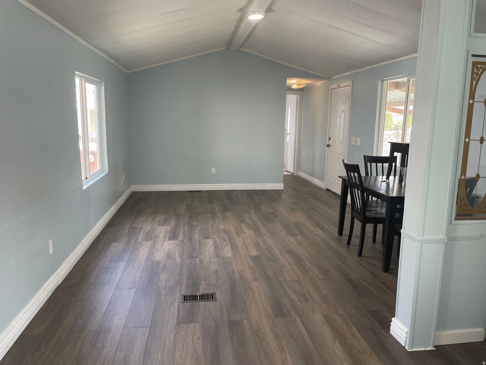 Unfurnished dining area featuring dark wood-style floors, ornamental molding, and beamed ceiling