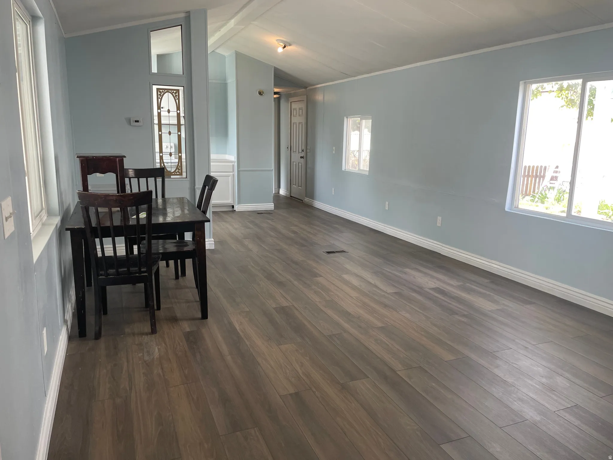 Dining space with dark wood-type flooring, healthy amount of natural light, crown molding, and beamed ceiling
