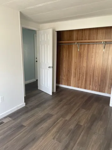 Unfurnished bedroom with dark wood-style floors and a closet