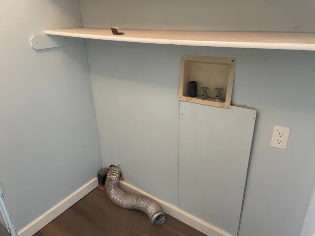 Laundry area featuring dark wood finished floors and baseboards