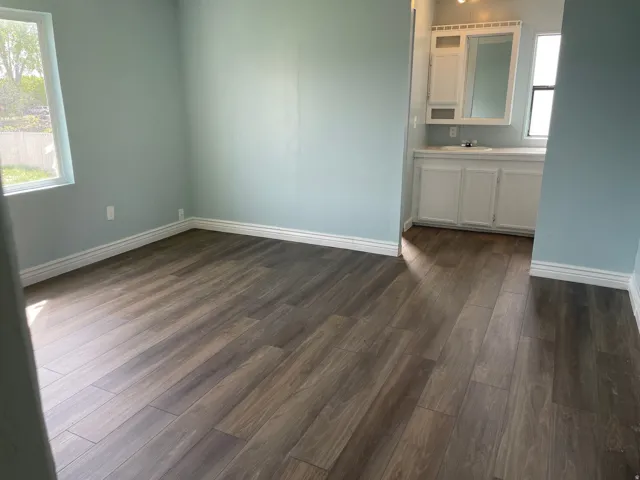 Unfurnished room featuring dark wood-style flooring and baseboards
