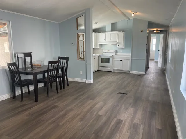 Dining space with beamed ceiling and dark wood-style floors