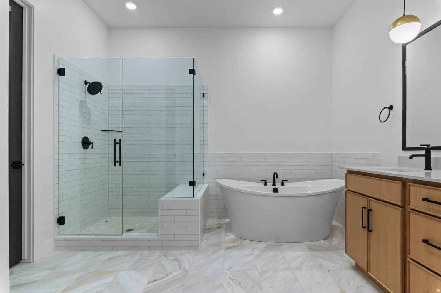 Bathroom featuring vanity, tile walls, a stall shower, a freestanding bath, and a wainscoted wall