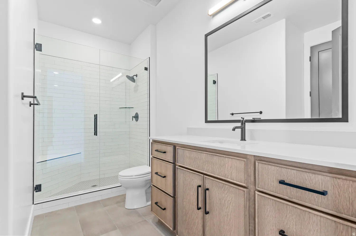 Full bath featuring vanity, a stall shower, recessed lighting, and light tile patterned floors