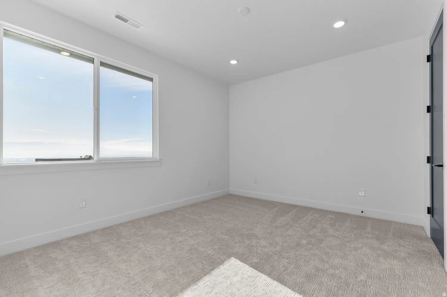 Empty room with light carpet and recessed lighting