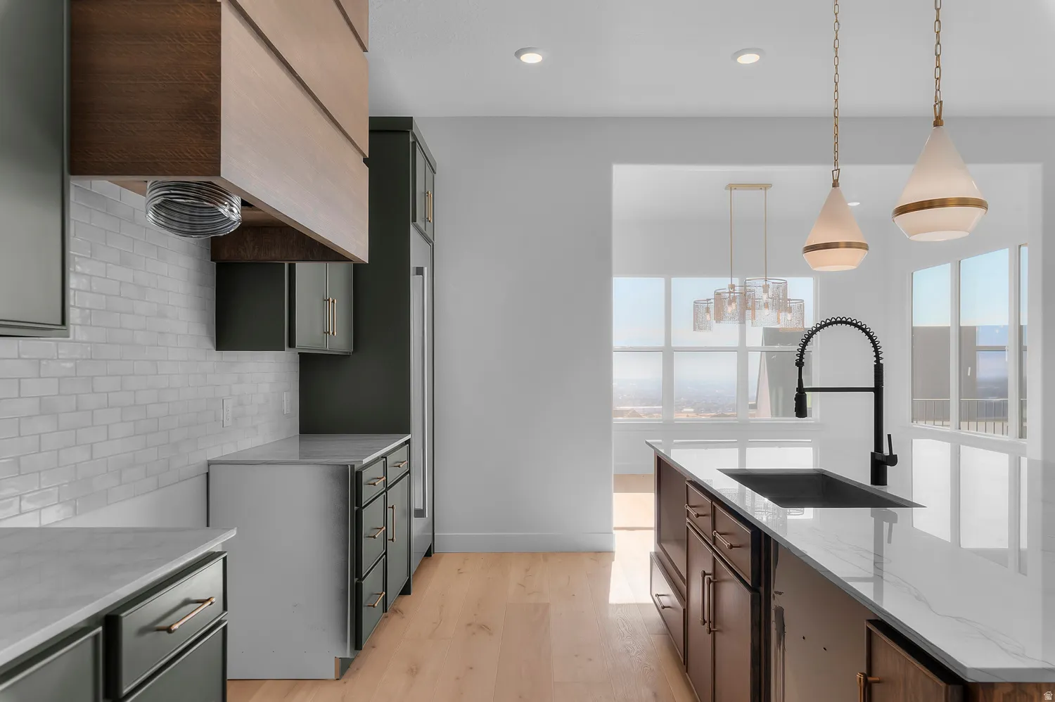 Kitchen with plenty of natural light, light wood finished floors, light stone countertops, and decorative light fixtures