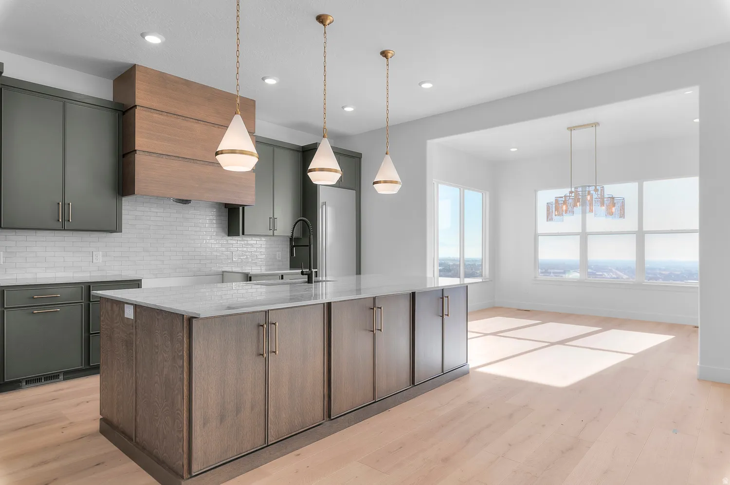 Kitchen with light stone counters, light wood-style floors, an island with sink, and decorative backsplash