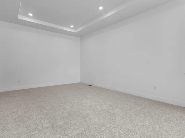 Spacious room featuring a tray ceiling with recessed lighting