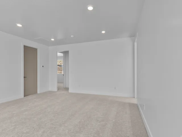 Spacious room featuring neutral wall finishes, recessed ceiling lighting, light-toned carpet flooring, and multiple doorway access points