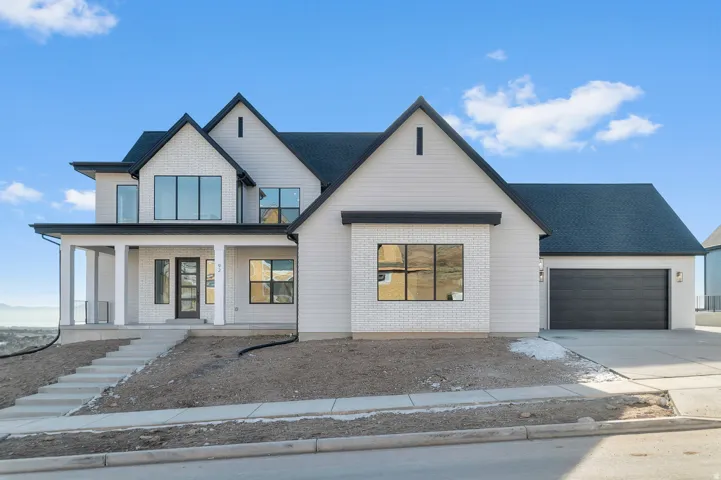Modern inspired farmhouse with a porch, concrete driveway, a garage, and brick siding