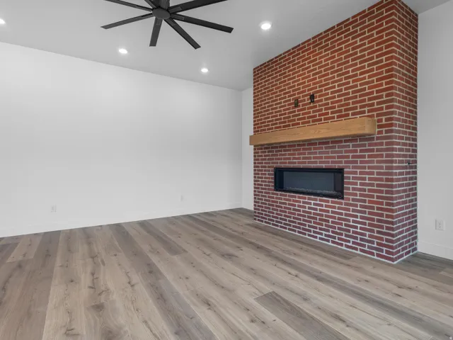 Accent brick wall featuring a linear electric fireplace with a wood mantel