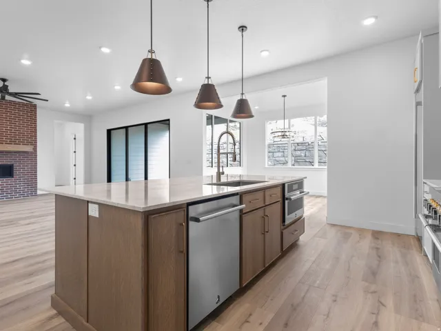 Kitchen island featuring a light-toned countertop, integrated stainless steel dishwasher, and built-in wall oven