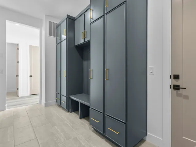 Custom built-in cabinetry in a deep grey finish featuring gold-toned hardware, offering extensive storage and an integrated bench seating area