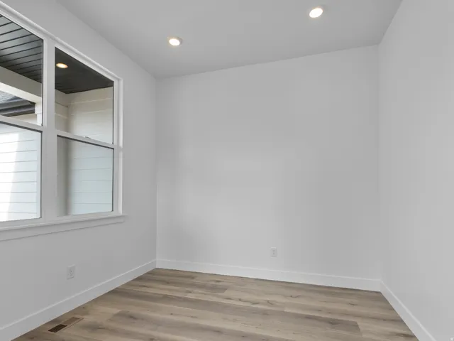 Crisp white walls define this space, featuring wood-finish flooring and modern recessed lighting