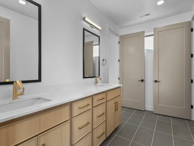 Double vanity with light wood-finish cabinetry and gold-tone hardware