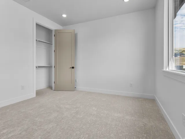 Carpeted room featuring a window, recessed lighting, and a closet with shelving and hanging rods