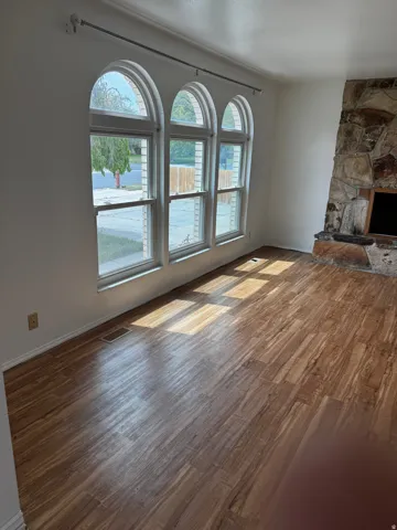 Unfurnished living room featuring healthy amount of natural light, dark wood-style flooring, and a fireplace
