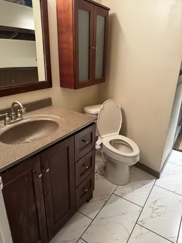 Half bath featuring light marble finish floors and vanity