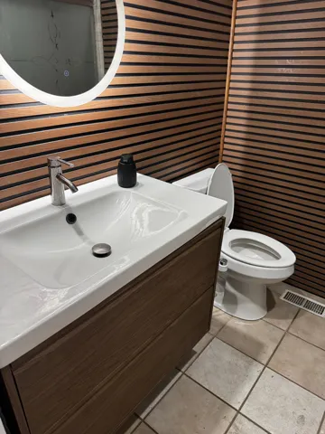 Bathroom with vanity, wallpapered walls, and light tile patterned floors