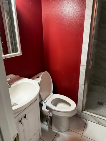Full bath with vanity, a shower stall, light tile patterned floors, and a textured wall