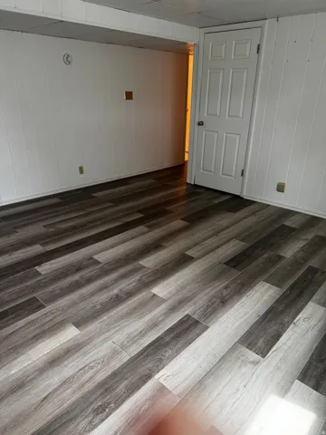 Unfurnished room featuring wood walls and dark wood-style flooring