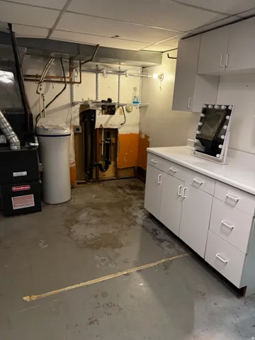 Unfinished below grade area featuring a paneled ceiling and a water softener