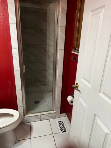 Bathroom featuring a shower stall and light tile patterned floors