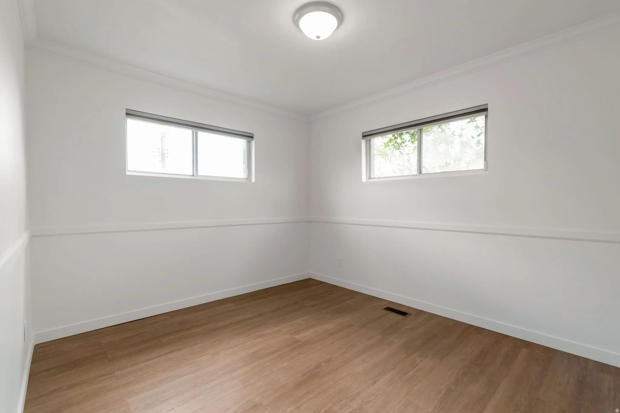 Unfurnished room featuring light wood-type flooring and crown molding