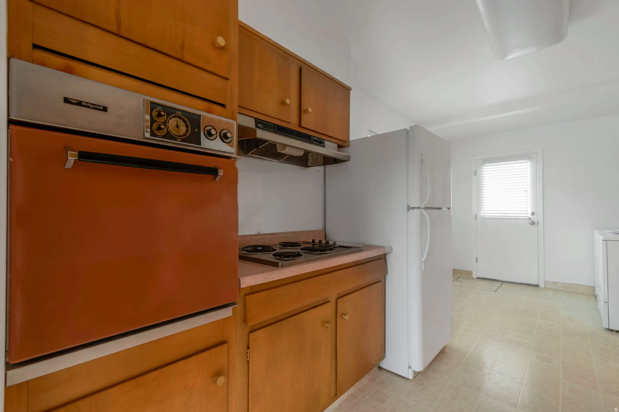 Kitchen featuring white appliances, light countertops, wood finish cabinets, light flooring, and washer / clothes dryer