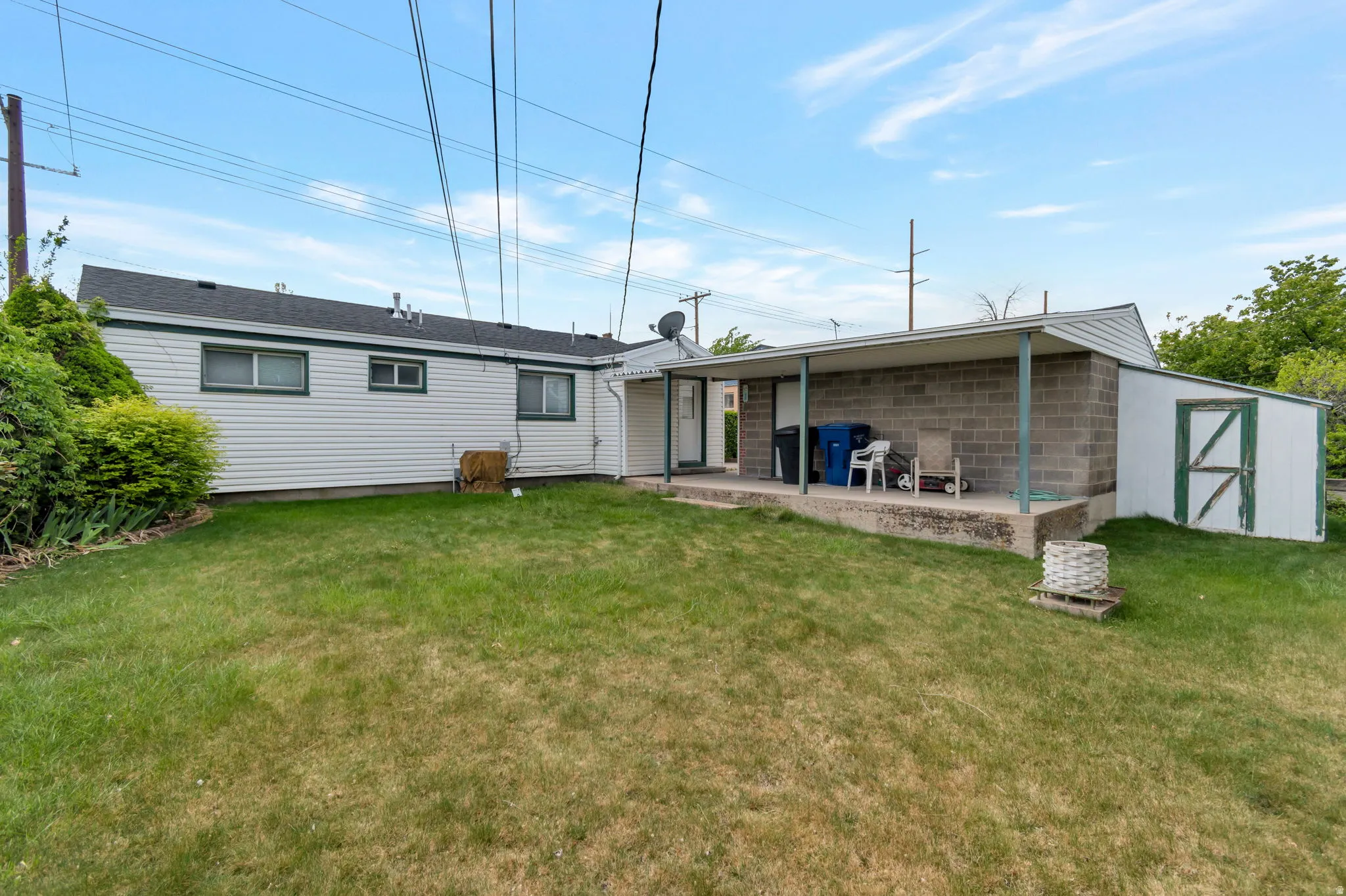 Back of property with a yard, concrete block siding, and a storage shed