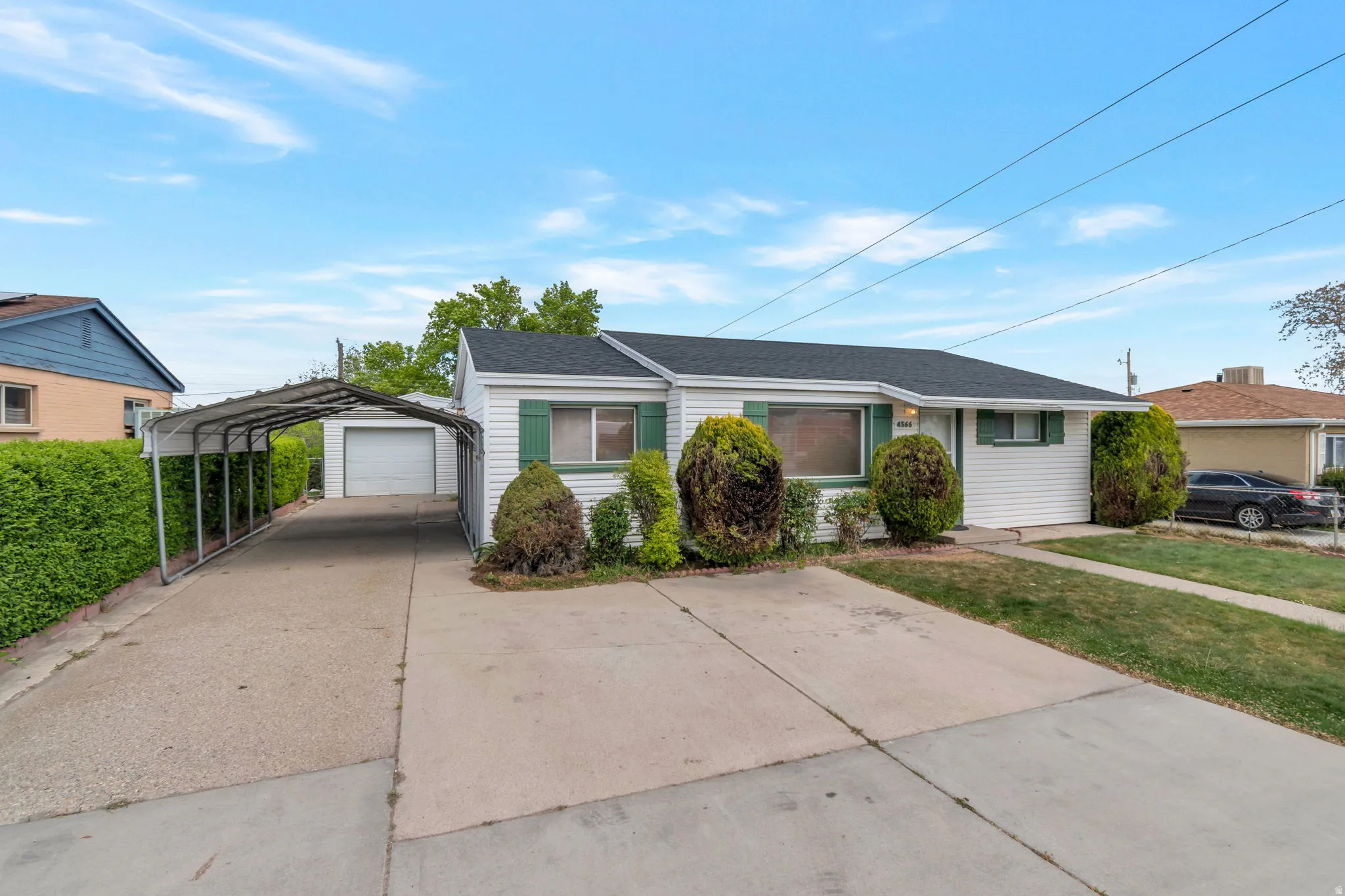 View of front of property with concrete driveway, a front yard, an outbuilding, and a shingled roof