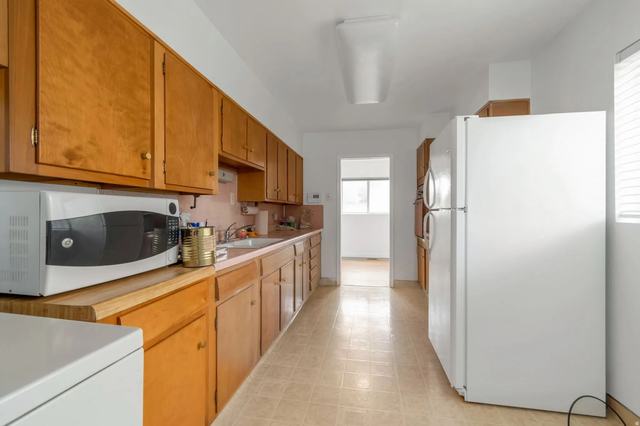 Kitchen with white appliances, light countertops, light flooring, and wood finish cabinetry