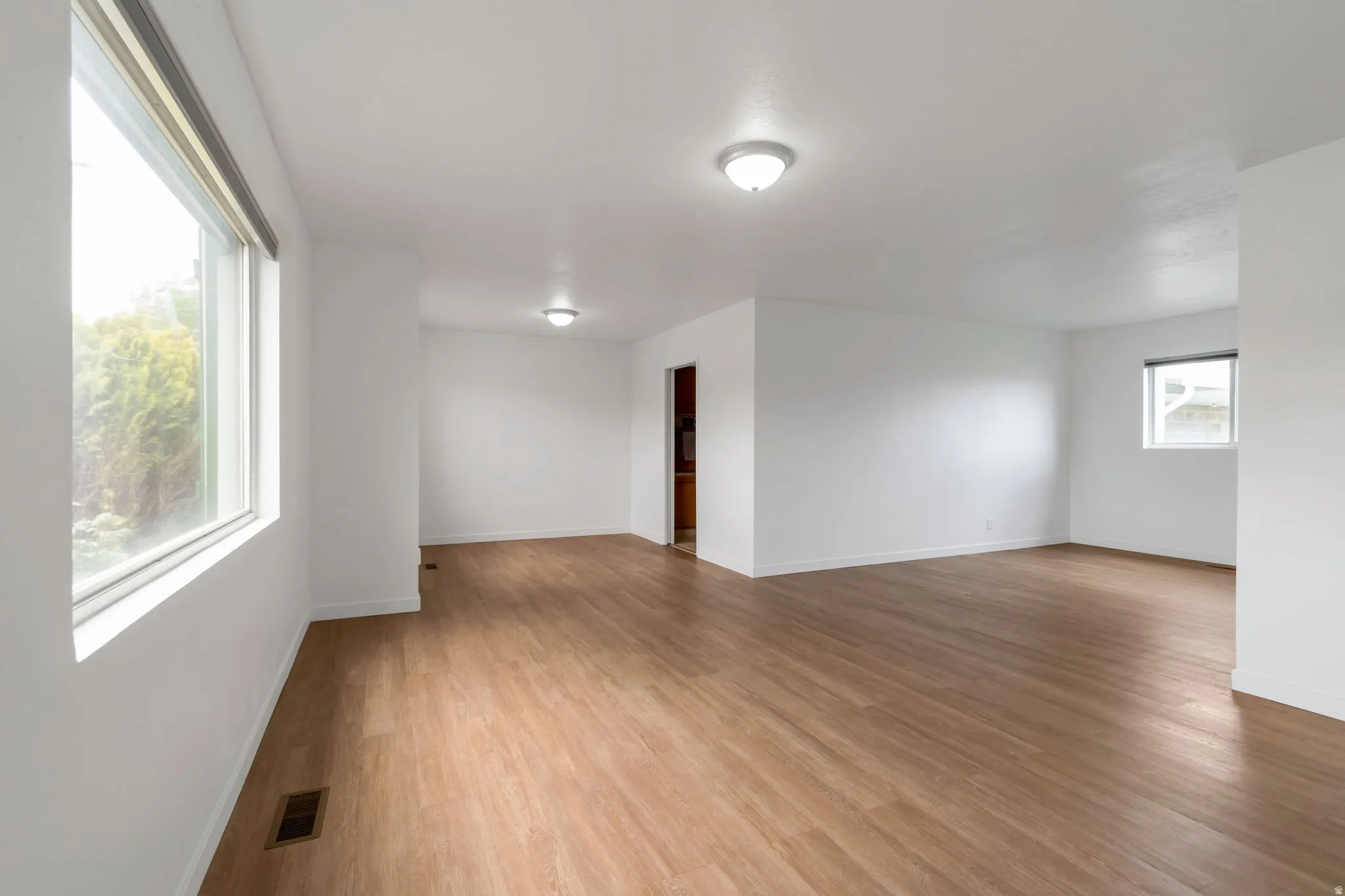 Spare room featuring light wood-style flooring and baseboards