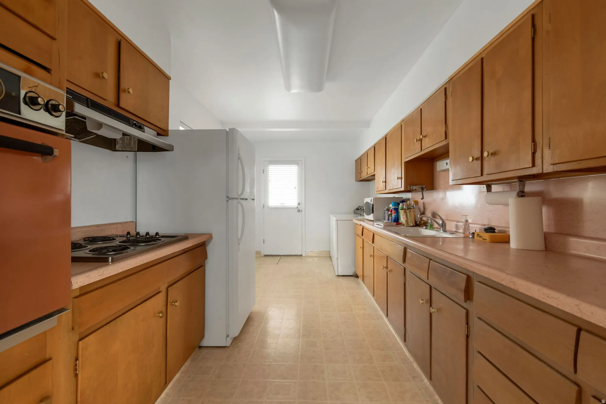 Kitchen featuring light flooring, freestanding refrigerator, light countertops, and wood finish cabinetry