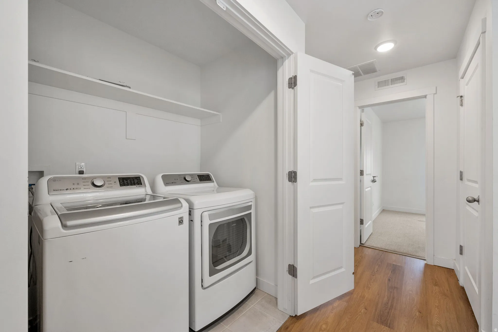 Laundry area with washer and clothes dryer and light wood-style floors