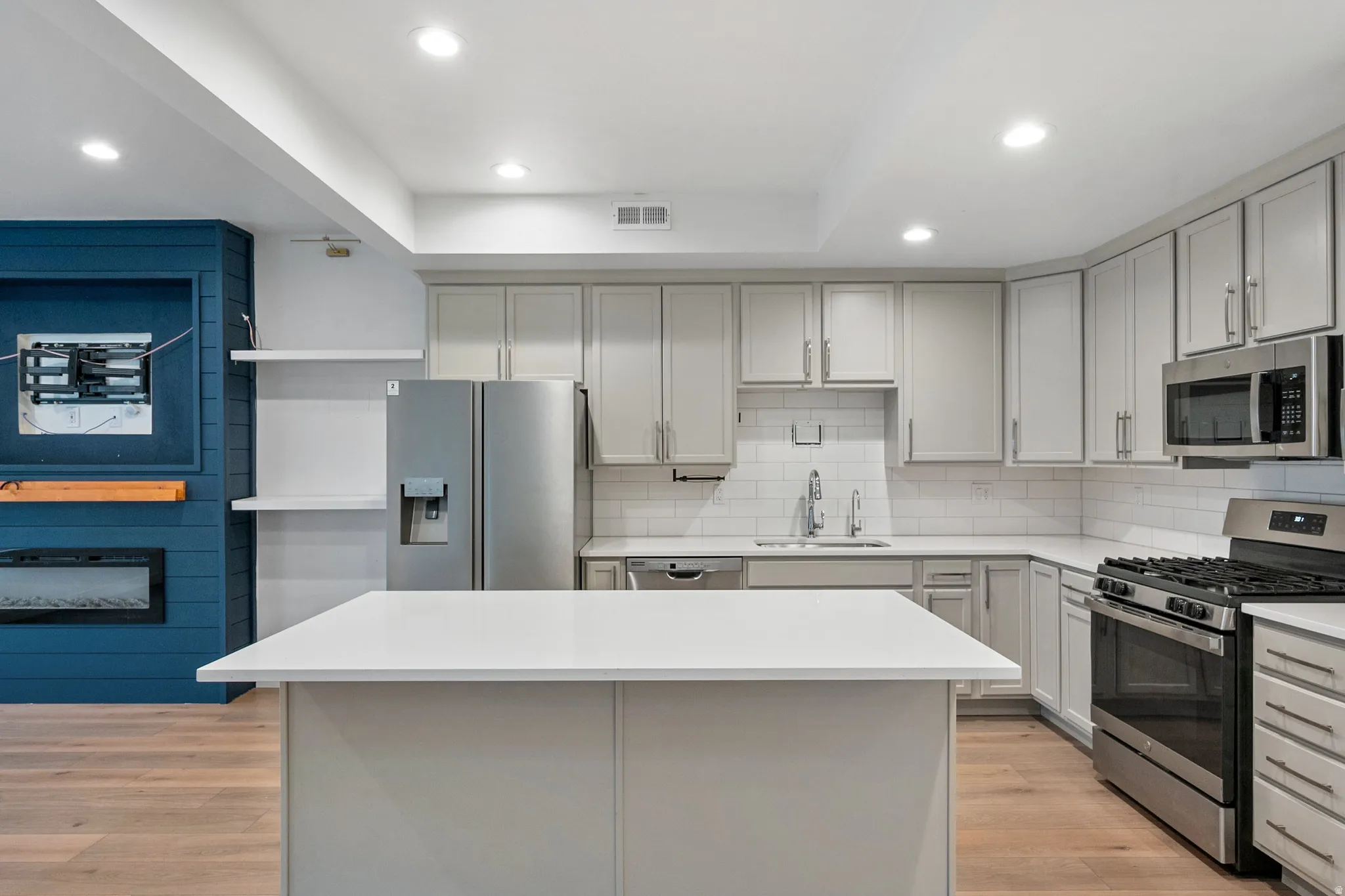 Kitchen featuring stainless steel appliances, a center island, light wood finished floors, recessed lighting, and decorative backsplash