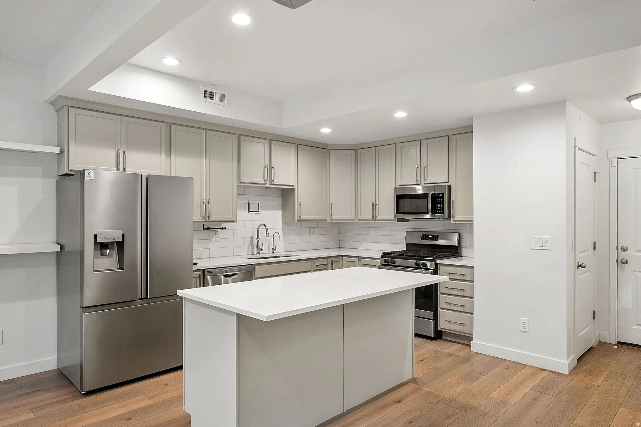 Kitchen featuring stainless steel appliances, light wood-style floors, gray cabinets, and recessed lighting