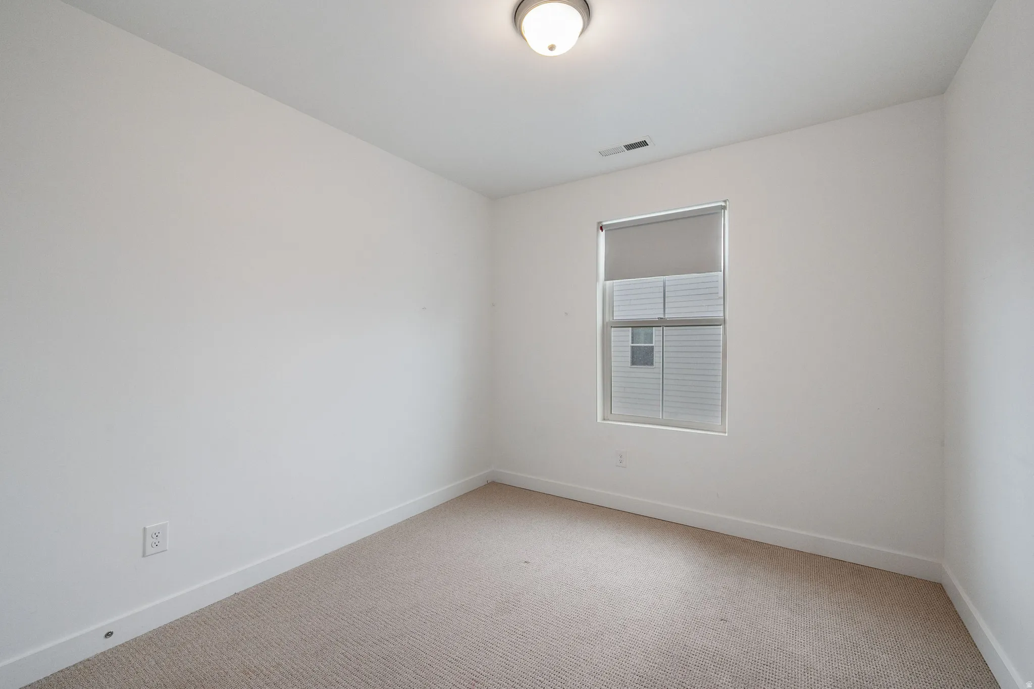 Empty room with light colored carpet and baseboards