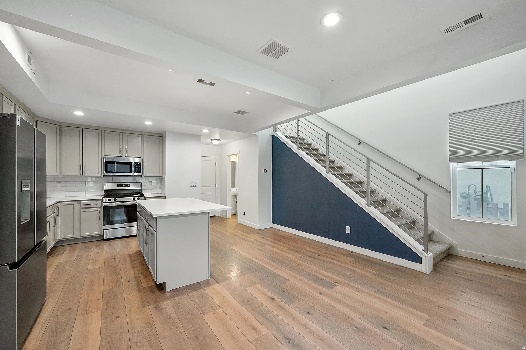Kitchen with gray cabinetry, stainless steel appliances, recessed lighting, a center island, and backsplash