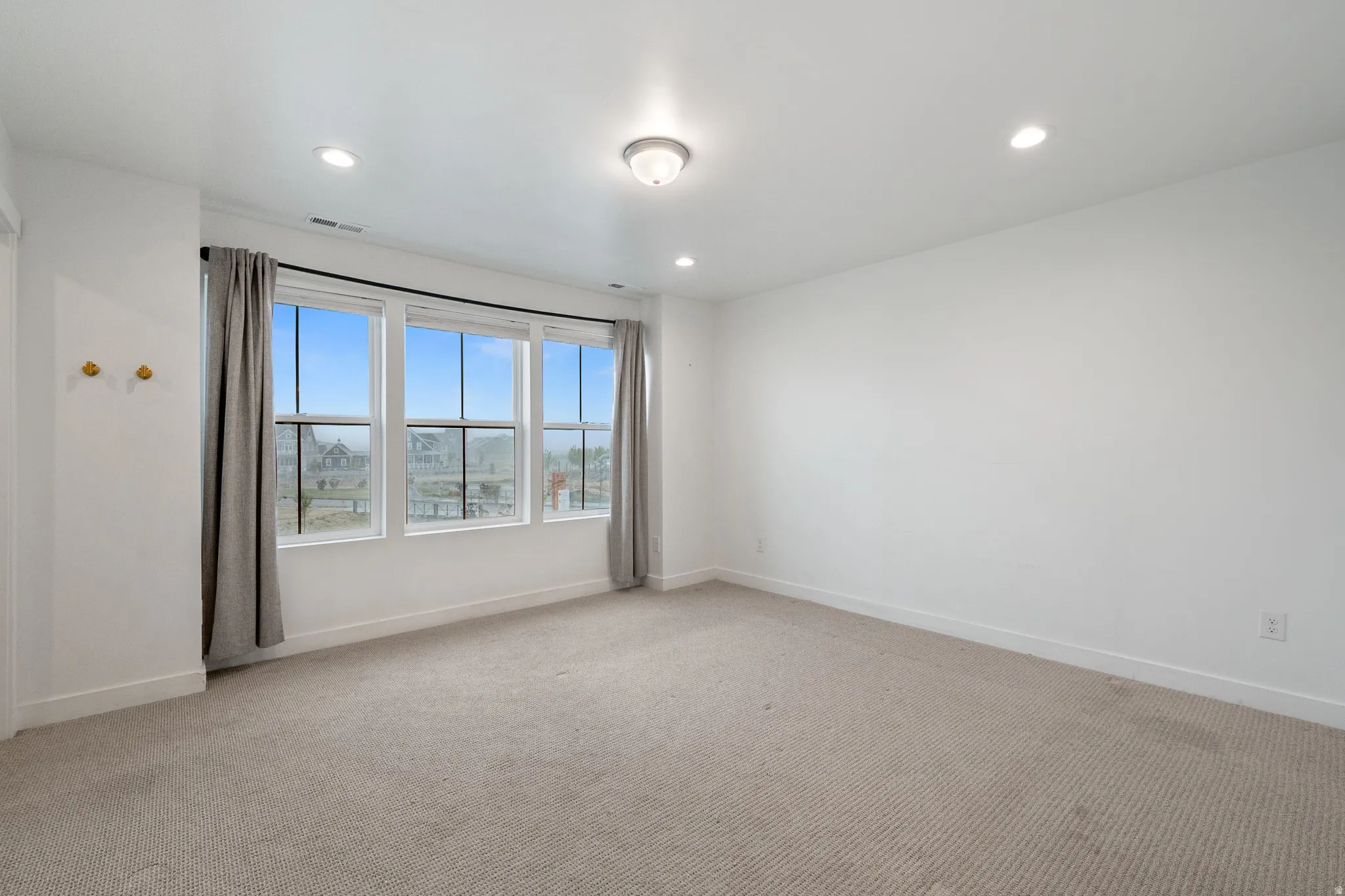 Empty room with light carpet and recessed lighting